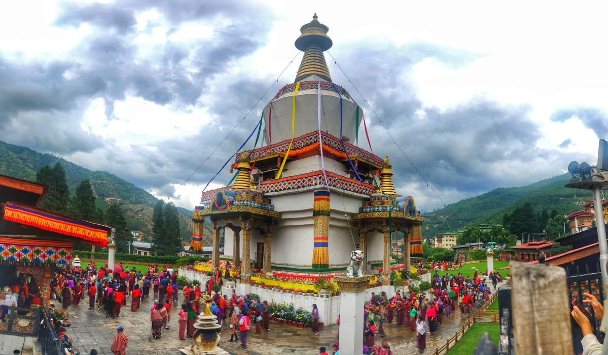 Group meditating at Himalayan sunrise with prayer wheels and monks
